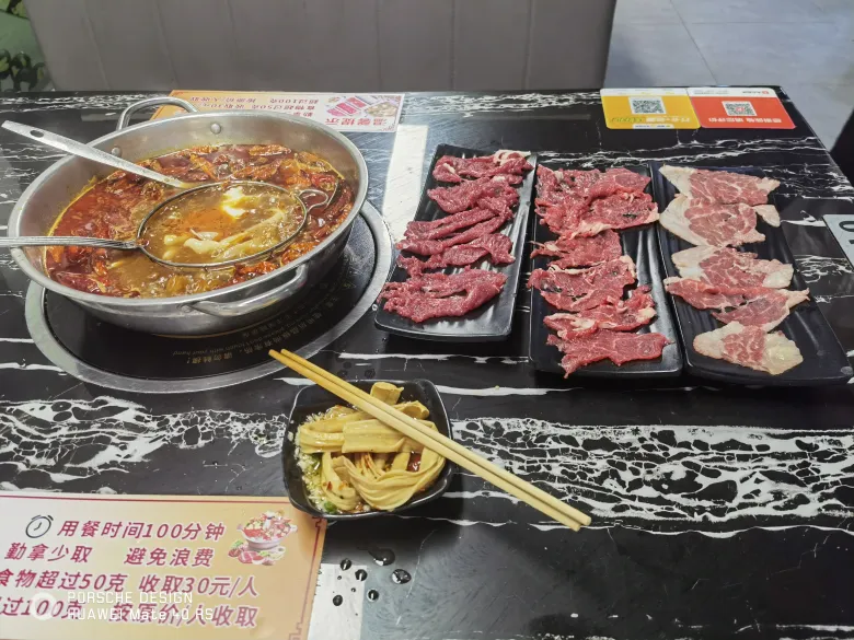 照片：生日当天吃的牛肉火锅自助，红油锅底旁摆着三盘现切牛肉、腐竹与蘸料。