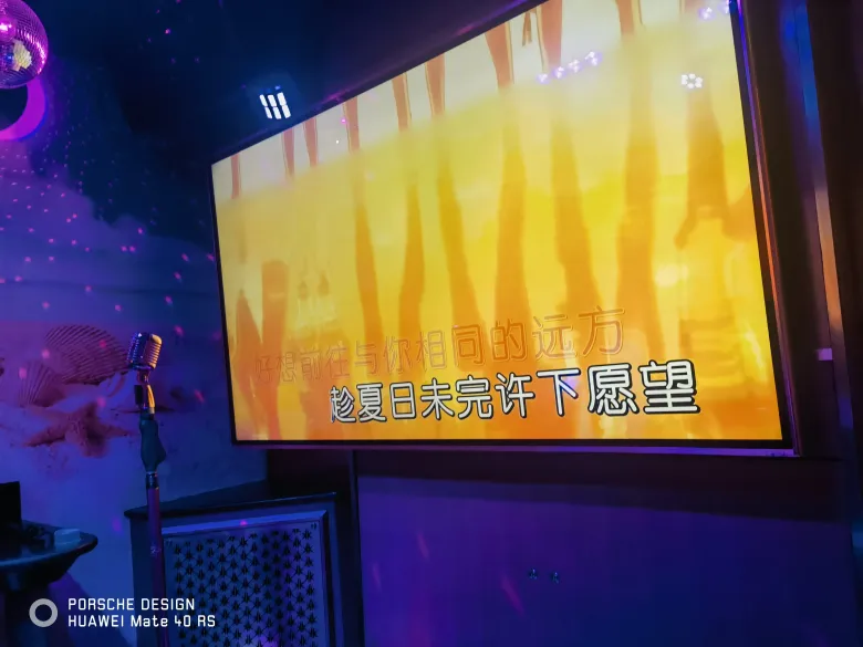 照片：KTV 包厢里屏幕显示歌词「趁夏日未完」，旁边立着麦克风。