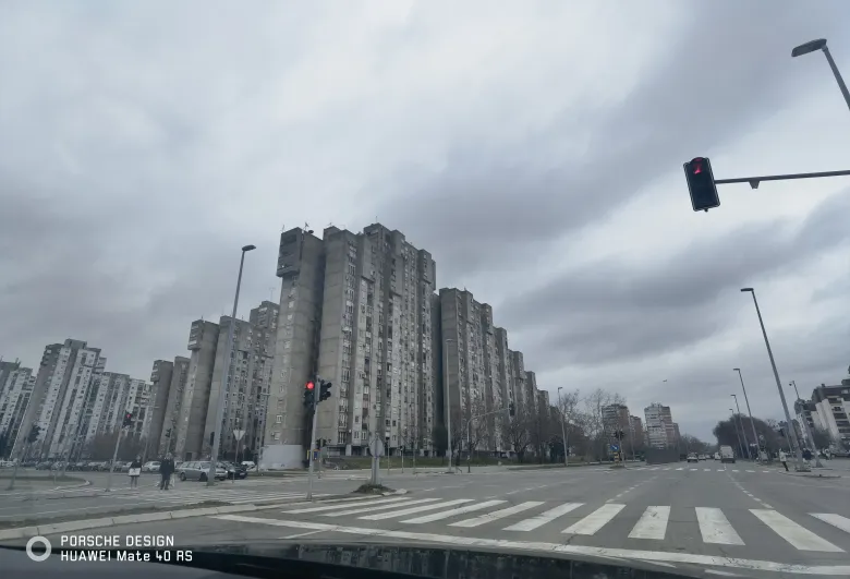 照片：贝尔格莱德街头成片的灰色高层居民楼，路口的红灯与斑马线清晰可见。