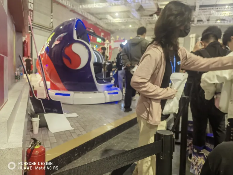 照片：展馆内的匹诺康尼主题 VR 座舱，紫色舱体印着梦境图案，观众在护栏旁排队。