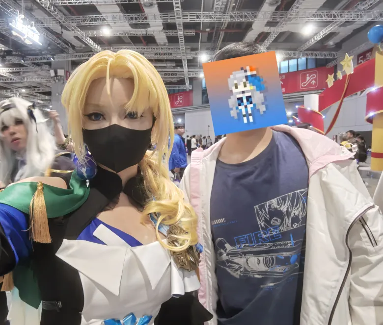 照片：金色长发的 coser 与同伴自拍合影，同伴的面部被像素风图案遮挡。